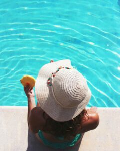 Woman at side of pool eating pineapple